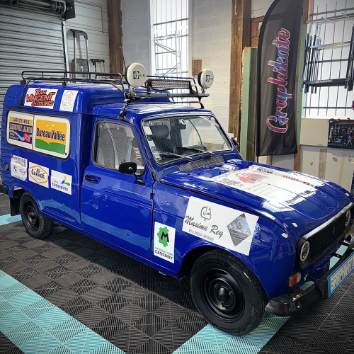Renault 4L trophy fourgonnette bleue avec logos des partenaires dans l'atelier Graphikate