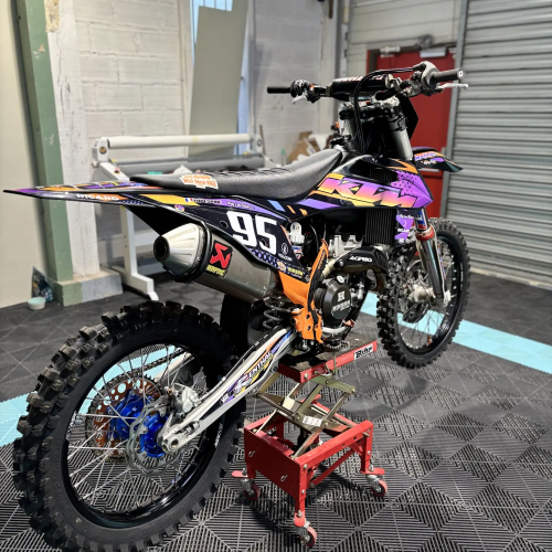 KTM 95 en kit déco violet et orange, vue trois-quarts arrière