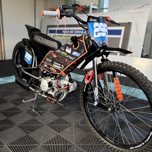 Moto de grasstrack habillée d'un kit déco orange, noir et bleu numéro 295