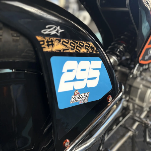 Plaque numéro latérale bleue 295 avec motif orange sur moto