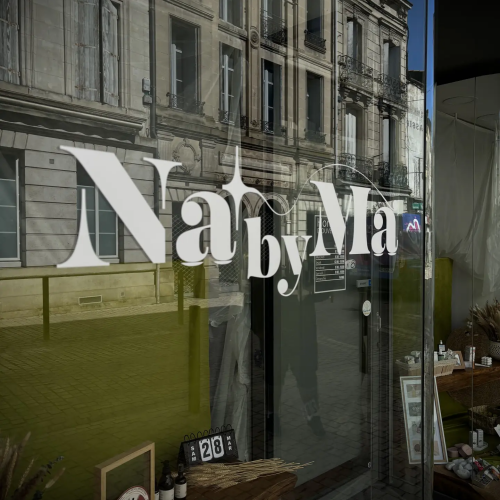 Lettrage adhésif blanc Na by Ma sur vitrine de boutique