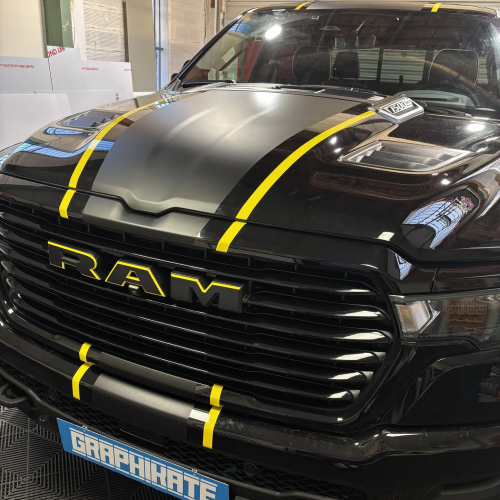 Pick-up RAM noir personnalisé avec bandes jaunes dans l'atelier Graphikate à Marmande